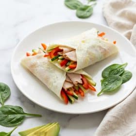 Egg white wraps filled with vegetables and turkey on white plate