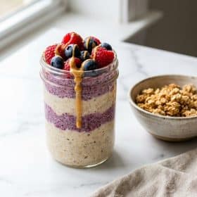Protein overnight oats in mason jar topped with berries