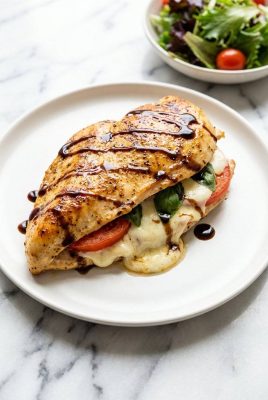 Close up of sliced caprese stuffed chicken with melted mozzarella and balsamic glaze