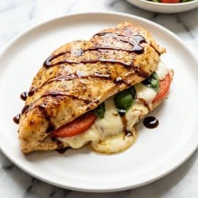 Close up of sliced caprese stuffed chicken with melted mozzarella and balsamic glaze