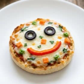 Close up of mini pizza face with veggie toppings