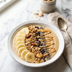 Peanut butter banana smoothie bowl with banana slices granola and chocolate chips