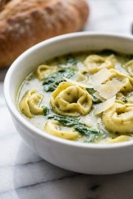 Close up of pesto tortellini soup with parmesan shavings