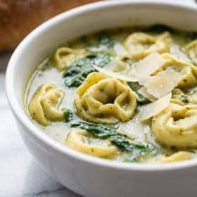 Close up of pesto tortellini soup with parmesan shavings