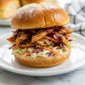 Extreme close up of pulled chicken slider showing shredded chicken coleslaw and BBQ sauce layers